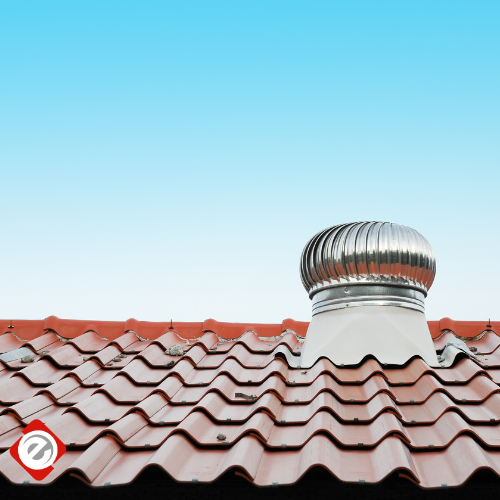 Rooftop with red tiles and a spinning silver turbine vent against a blue sky.