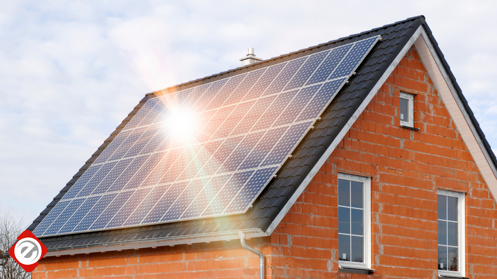 Solar panels on a red brick house roof, bright sunlight.