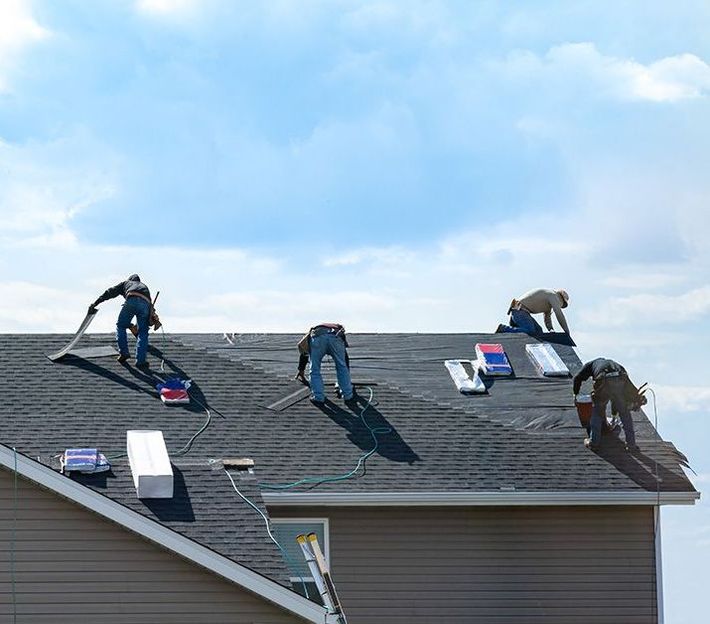 A group of men are working on the roof of a house.