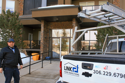 A man standing next to a white truck that says link