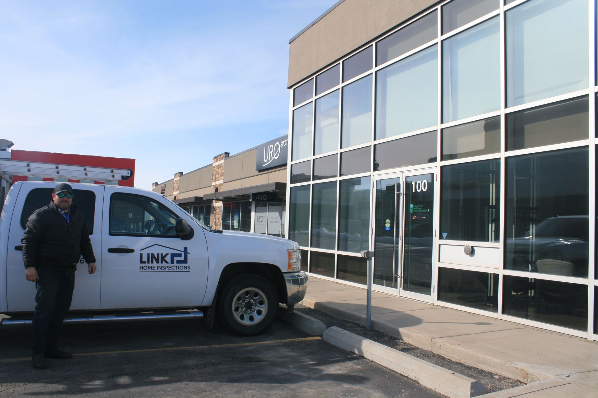 A white truck with the word link on the side is parked in front of a building