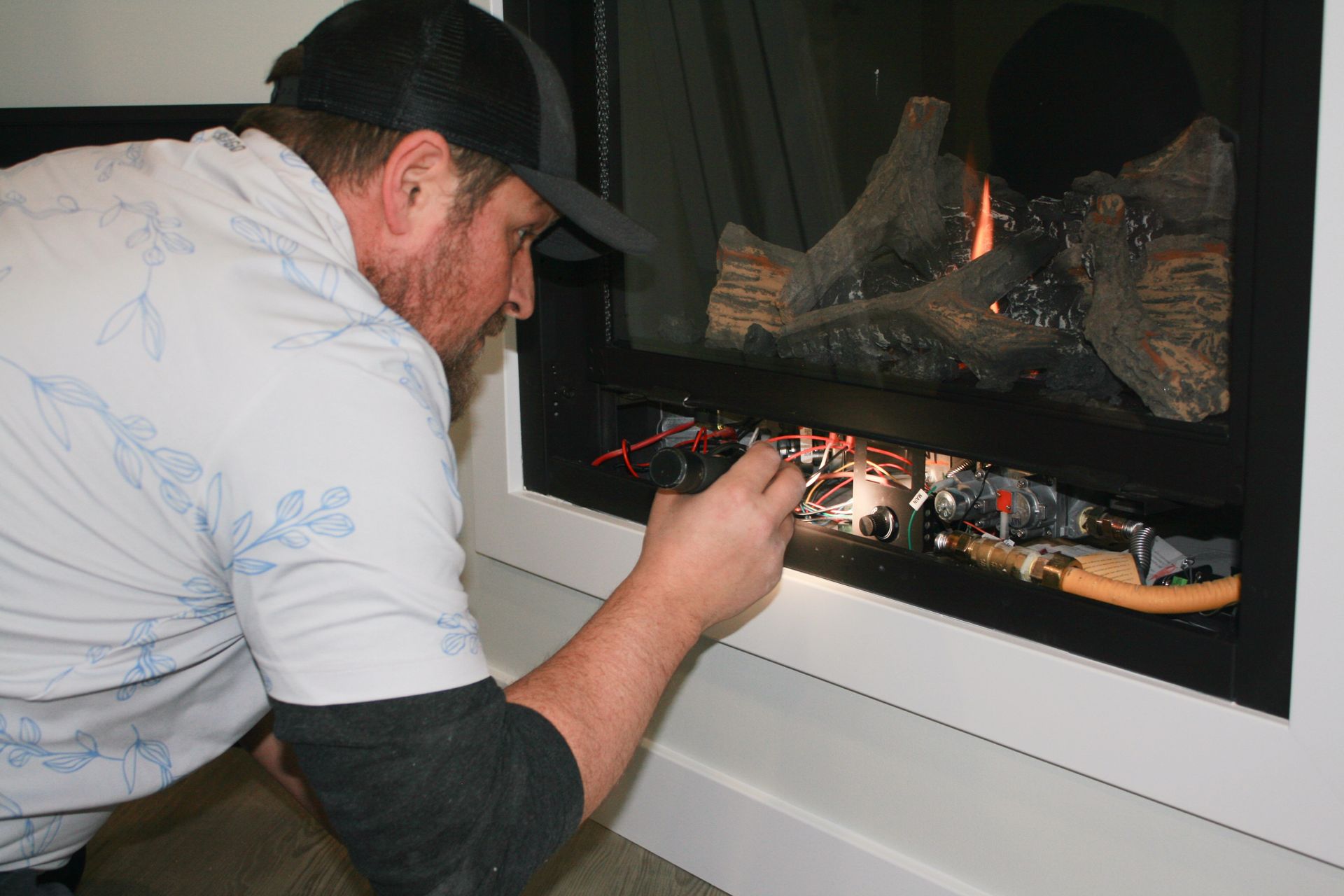 A man is working on a fireplace with a flashlight.
