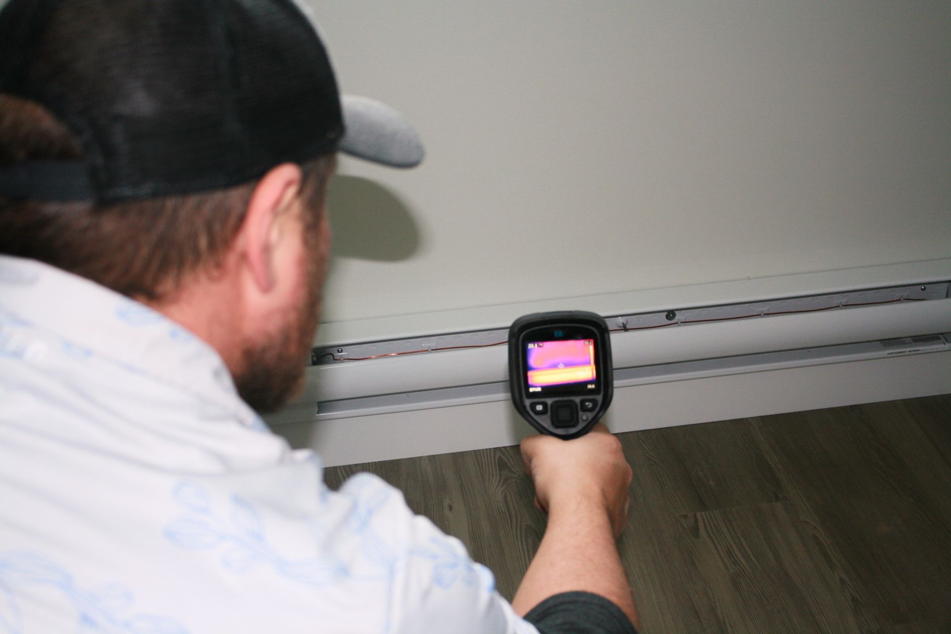 A man is using a thermal camera to check the temperature of a wall.