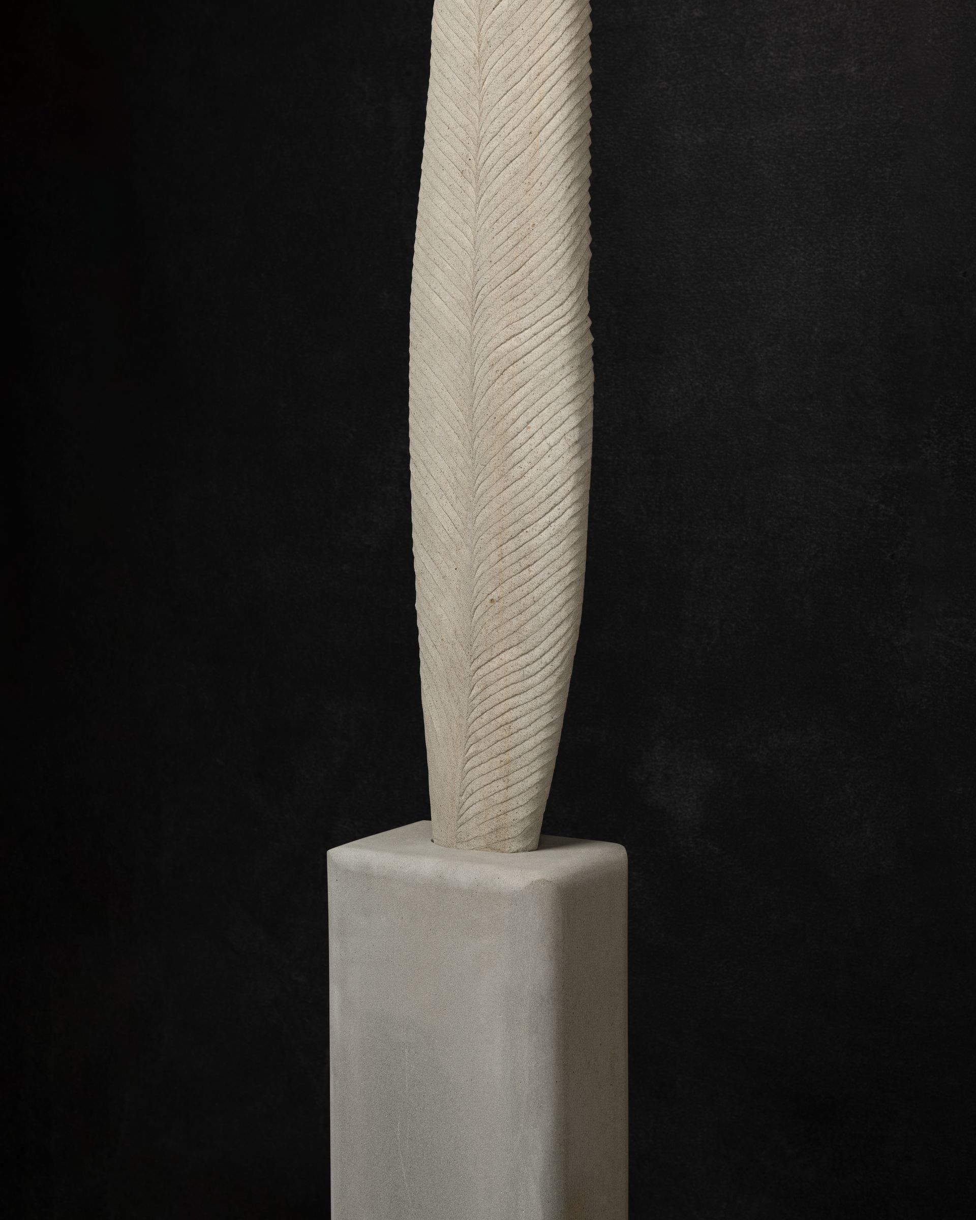 A white sculpture is sitting on top of a white block on a black background.
