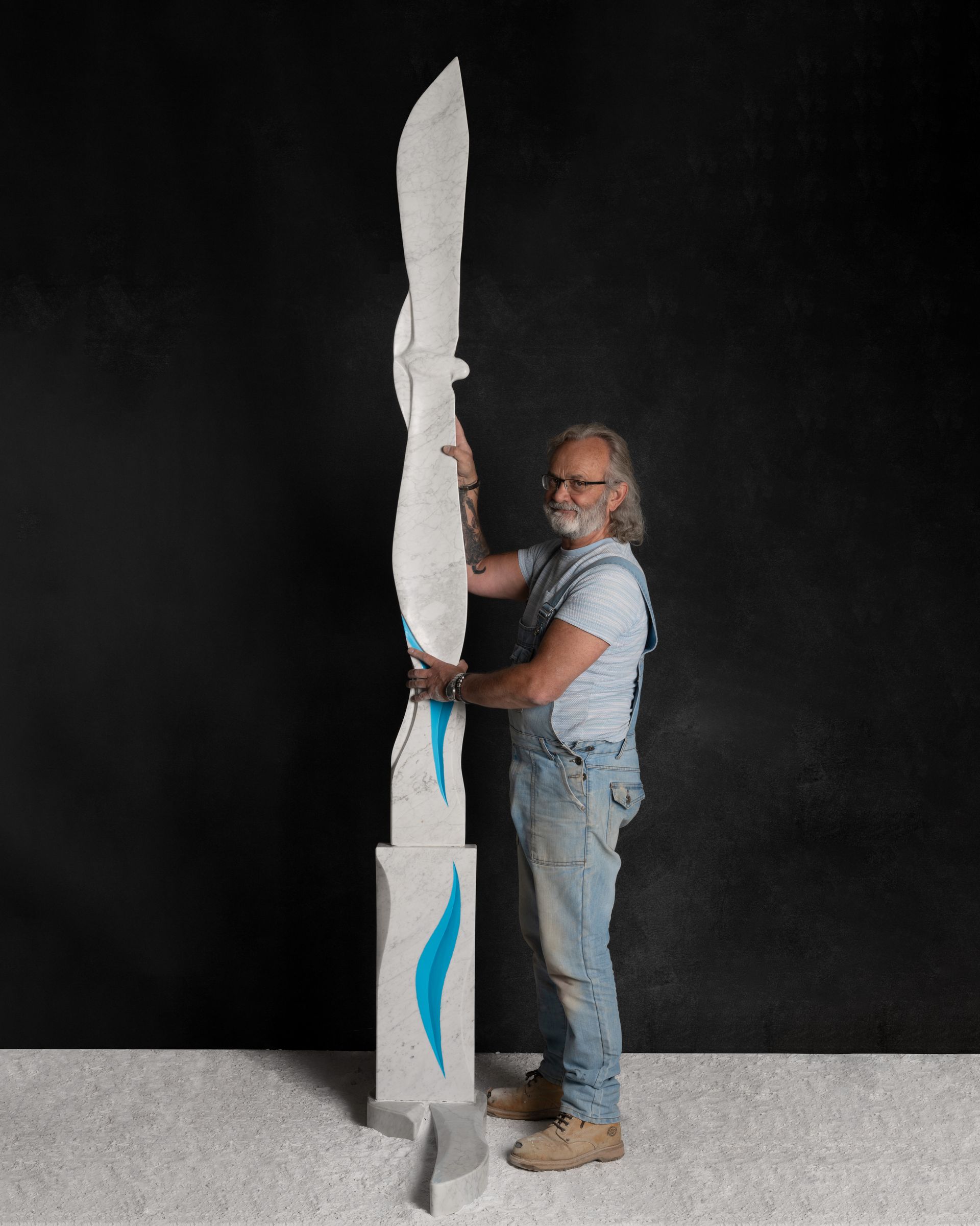 A man is standing next to a large white marble sculpture