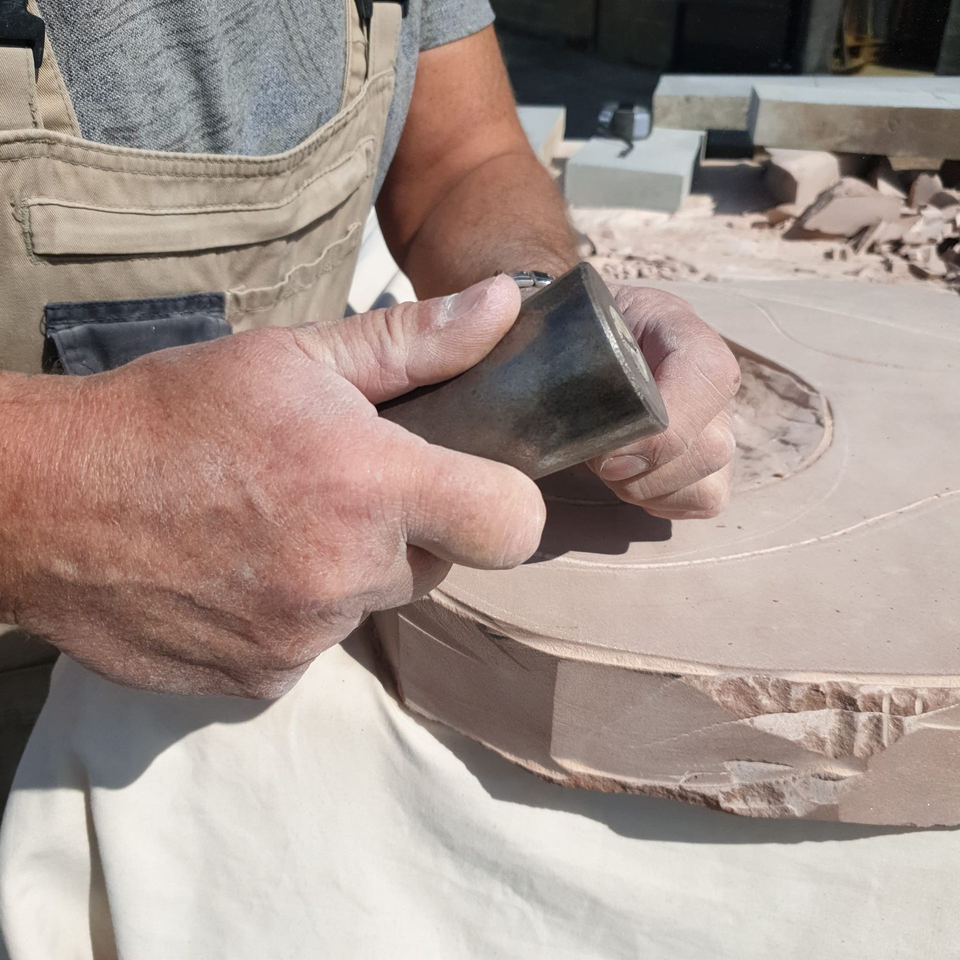 A man is working on a piece of stone with a chisel and hammer