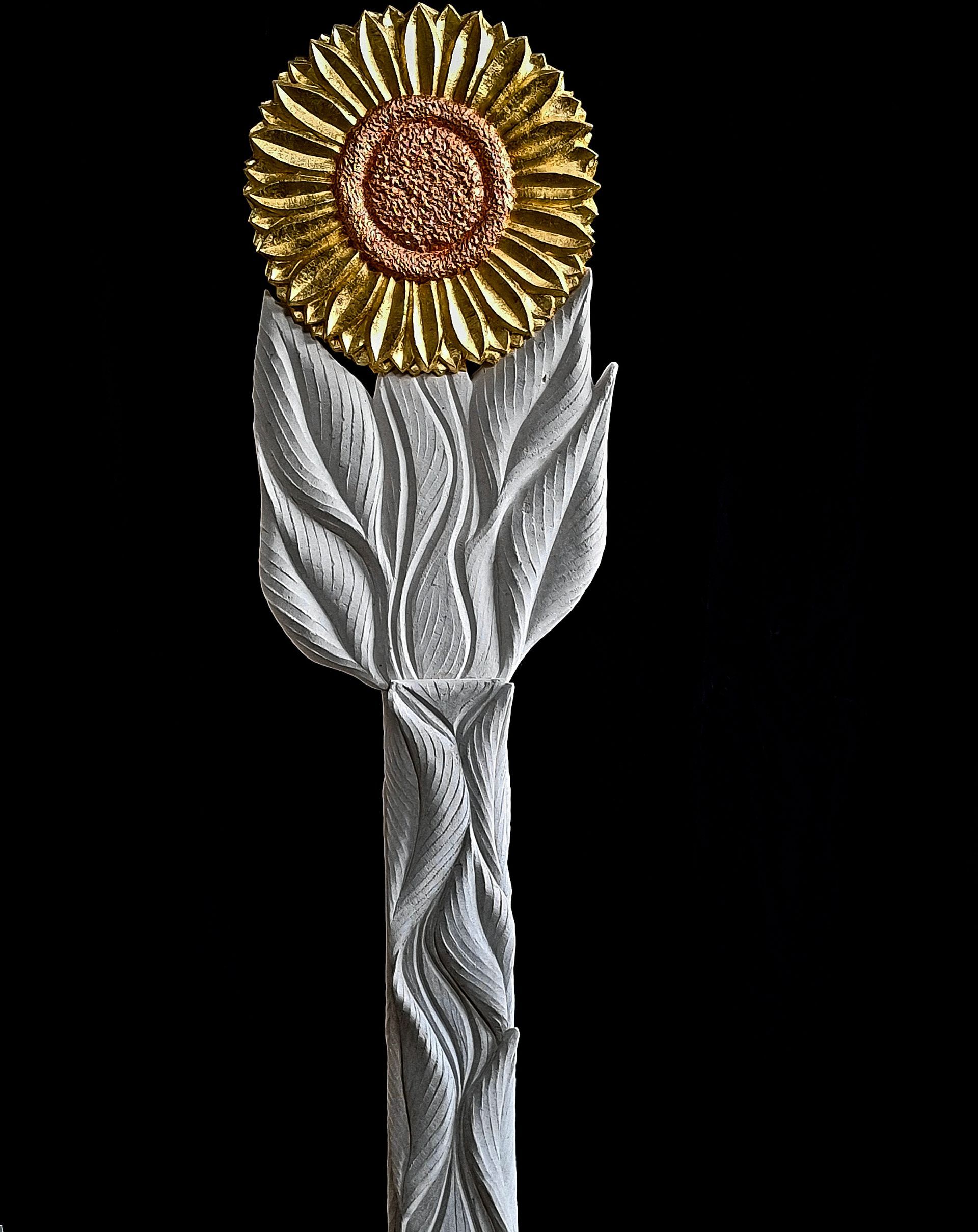 A statue of a sunflower with leaves on a black background.