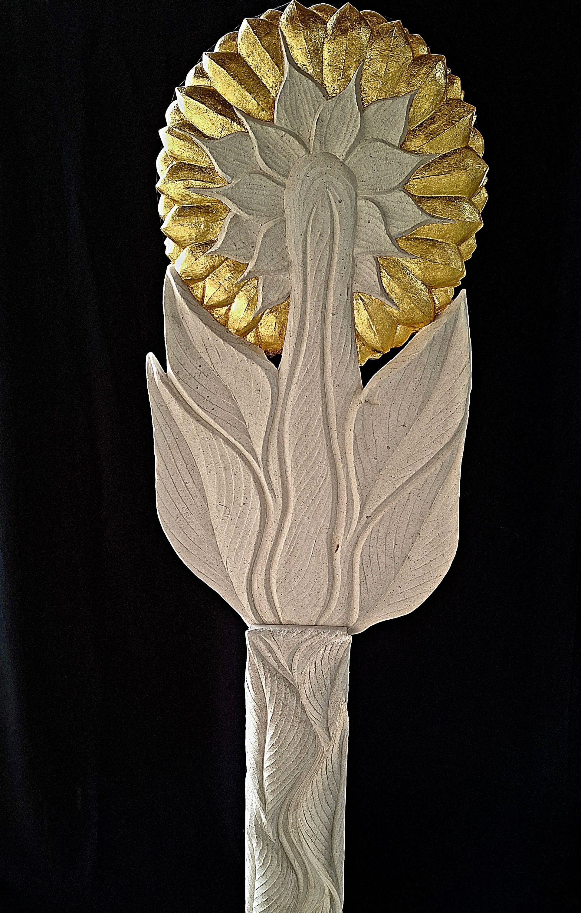 A statue of a sunflower with leaves on a black background.