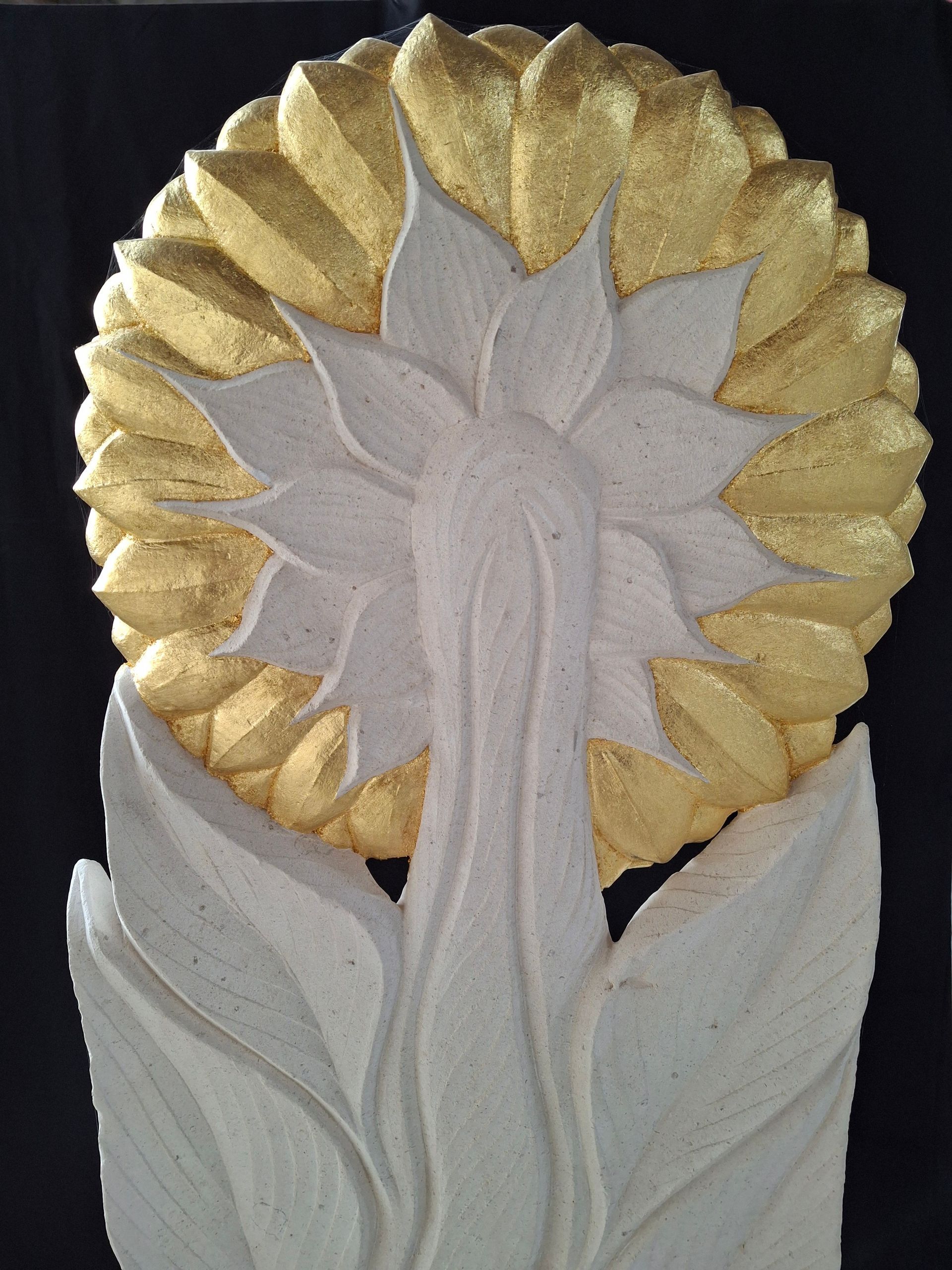 White flower sculpture with gold-tipped petals and layered leaves on a decorative base
