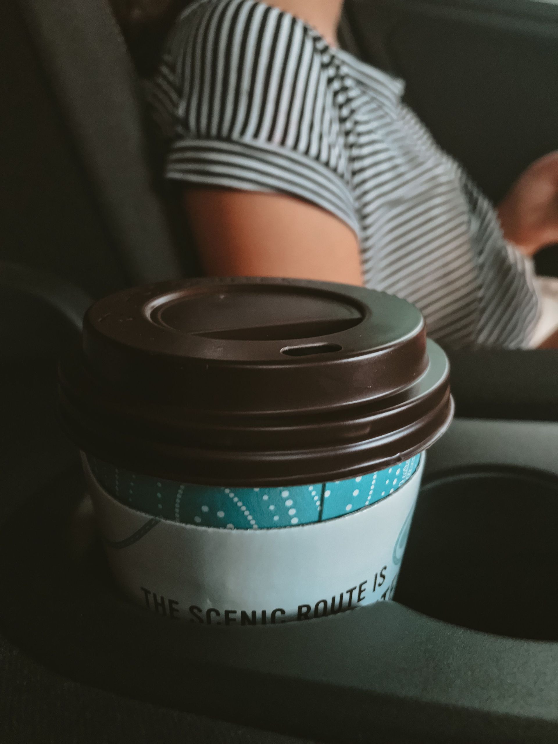Coffee in holder next to a woman driving
