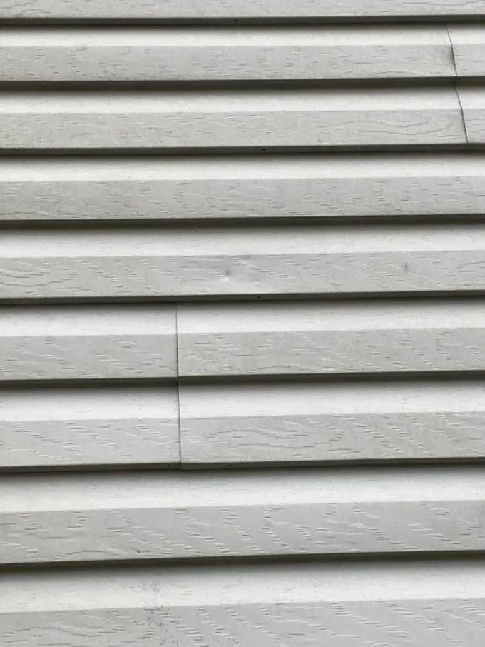 White horizontal siding with a vertical seam and textured surface close-up