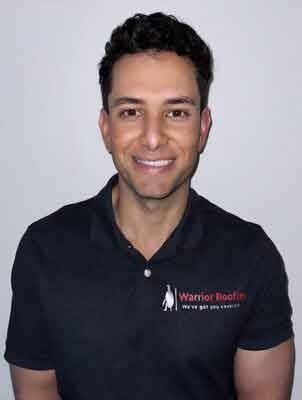 Smiling man in a black polo shirt against a light gray background