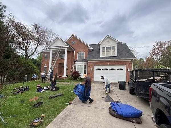 Workers installing decorations on a suburban house lawn and driveway, with tools and truck nearby