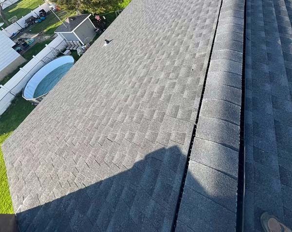 Roof shingles viewed from above, with a shadow and a backyard pool visible along the edge.
