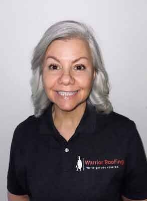 Smiling woman in a black Warrior Roofing polo shirt against a plain light background