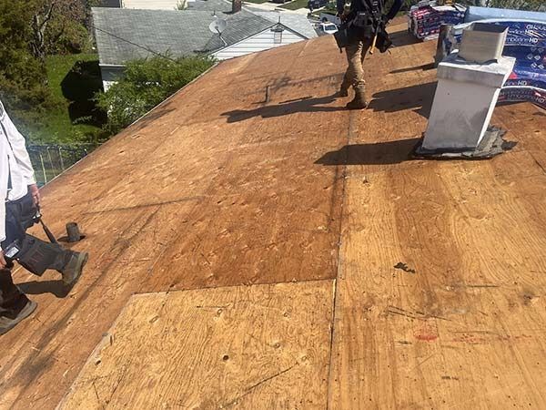 Workers installing new wooden roofing on a house roof under bright sunlight