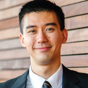 a man in a suit and tie is smiling for the camera .