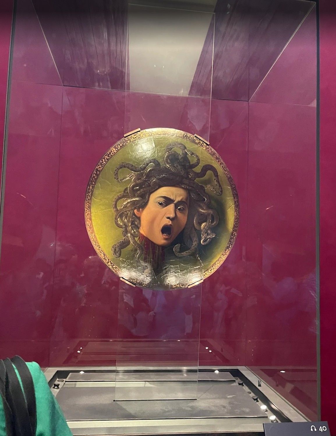 Circular portrait of a shouting face inside a clear glass display case with a magenta backdrop