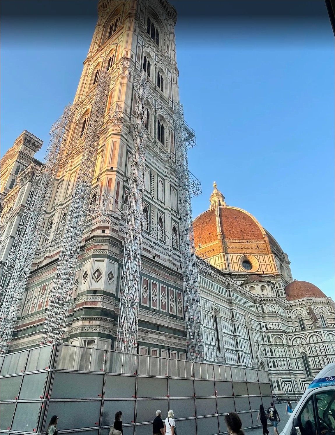 Florence Cathedral’s ornate bell tower and red dome against a blue sky, with people below
