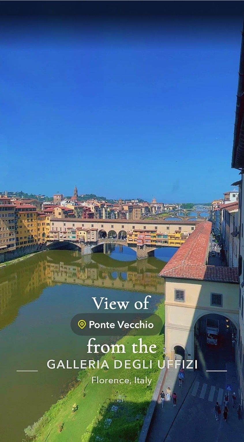 View of the Ponte Vecchio and Arno River in Florence, with Galleria degli Uffizi under a blue sky