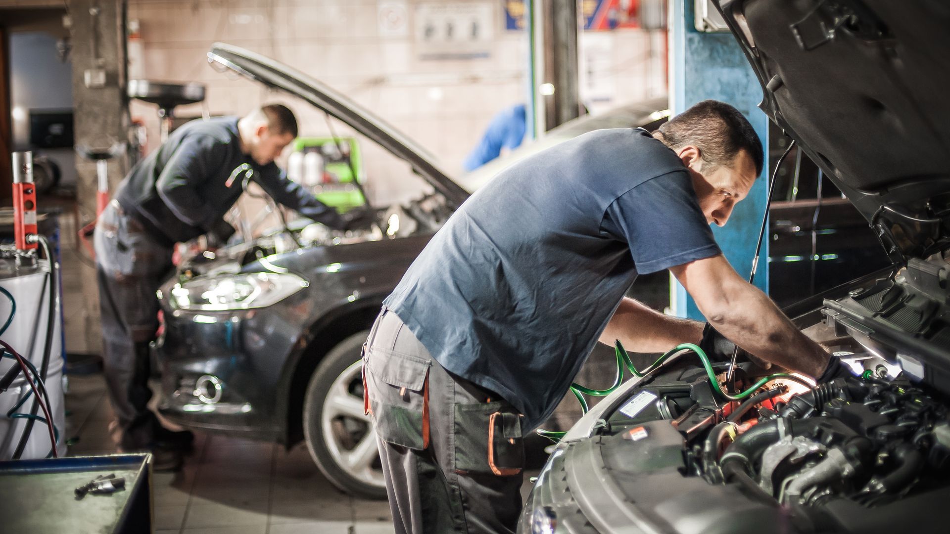 Deux mécaniciens travaillent sur une voiture dans un garage.