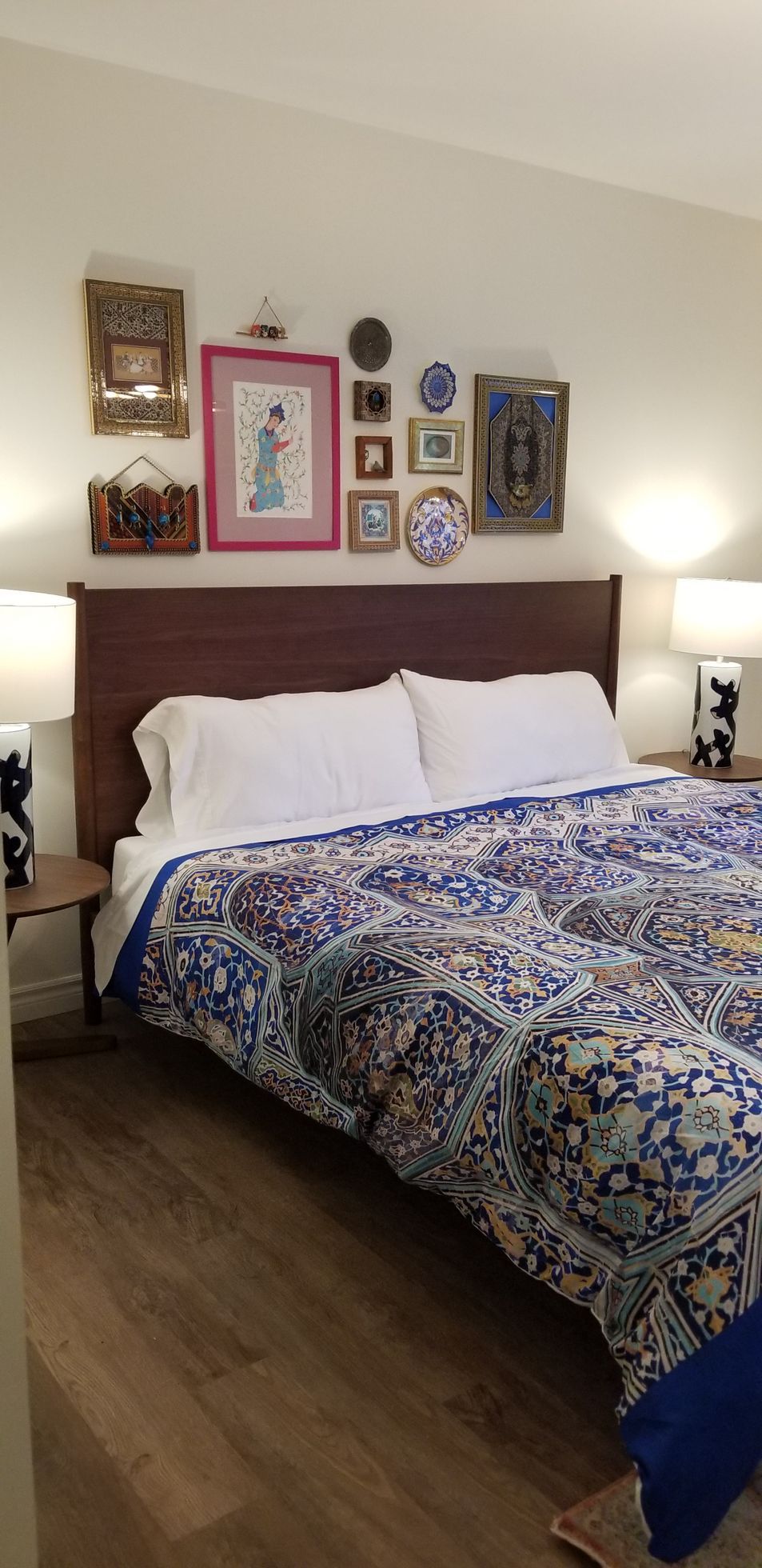 Cozy bedroom with a large bed, patterned quilt, white pillows, and framed wall art above the headboard