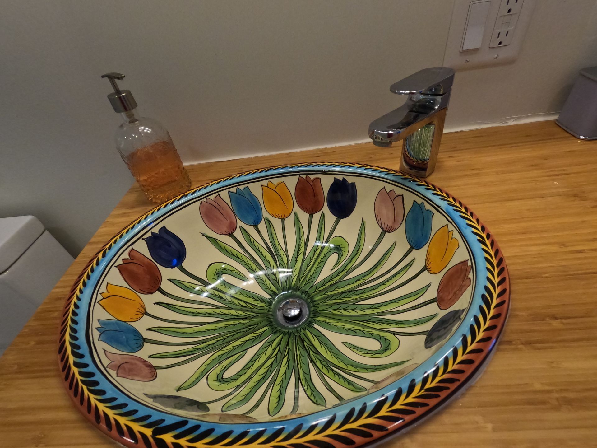 Colorful mosaic bathroom sink with floral tulip pattern and a chrome faucet on a wooden countertop