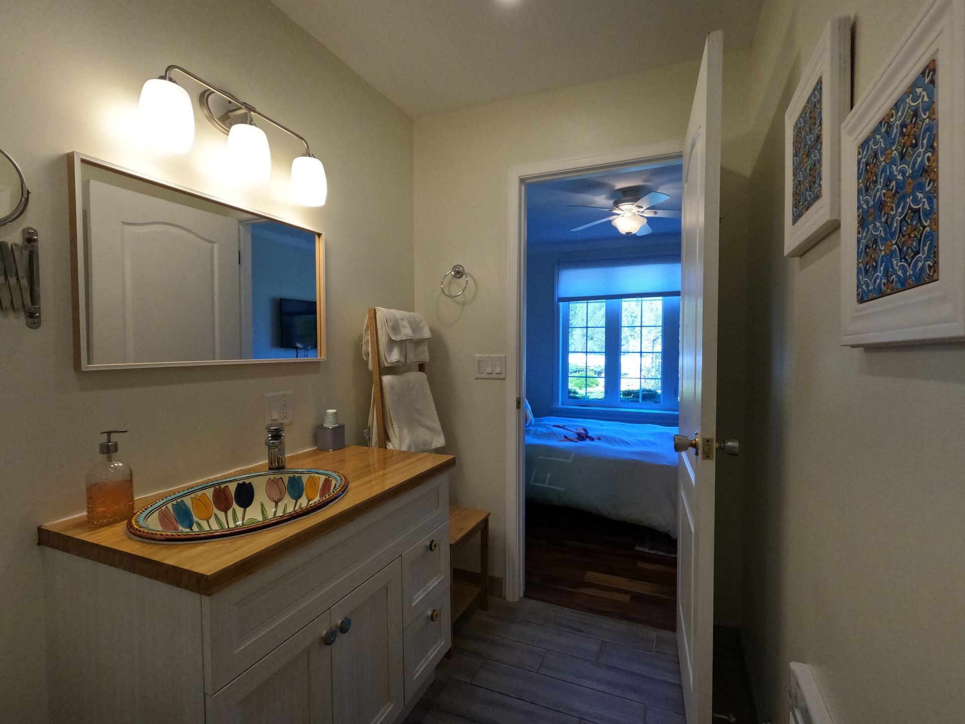 Bathroom vanity with sink, mirror, lights, and a doorway to a blue bedroom beyond.