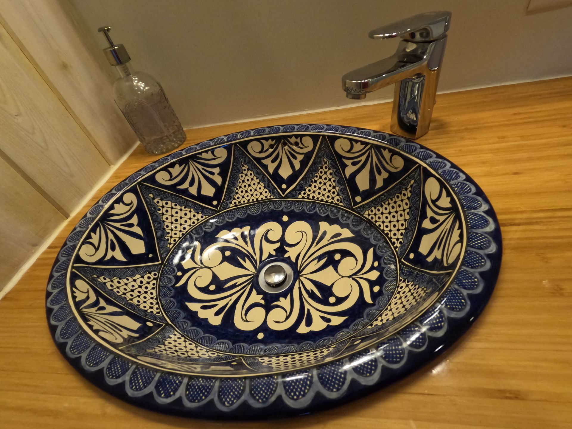Blue-and-cream patterned ceramic sink with chrome faucet on a wooden countertop