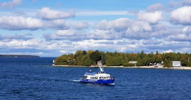 White ferry deck on calm water with mountains and cloudy sky in the background