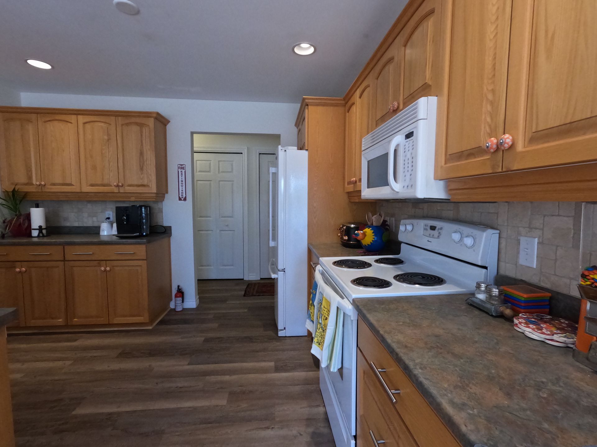 Bright kitchen with wood cabinets, white stove and microwave, and a tiled countertop.