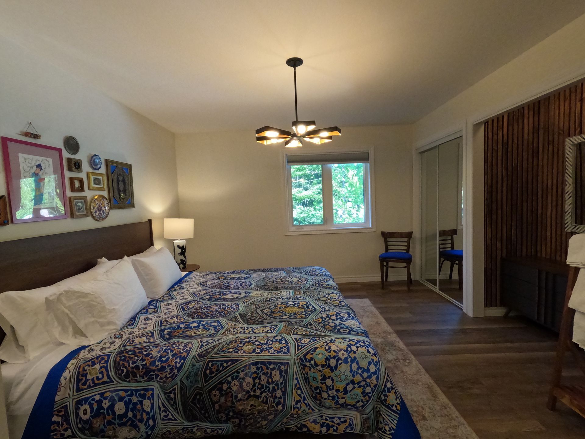 Hotel bedroom with two beds, patterned bedding, a lamp, window, and seating area