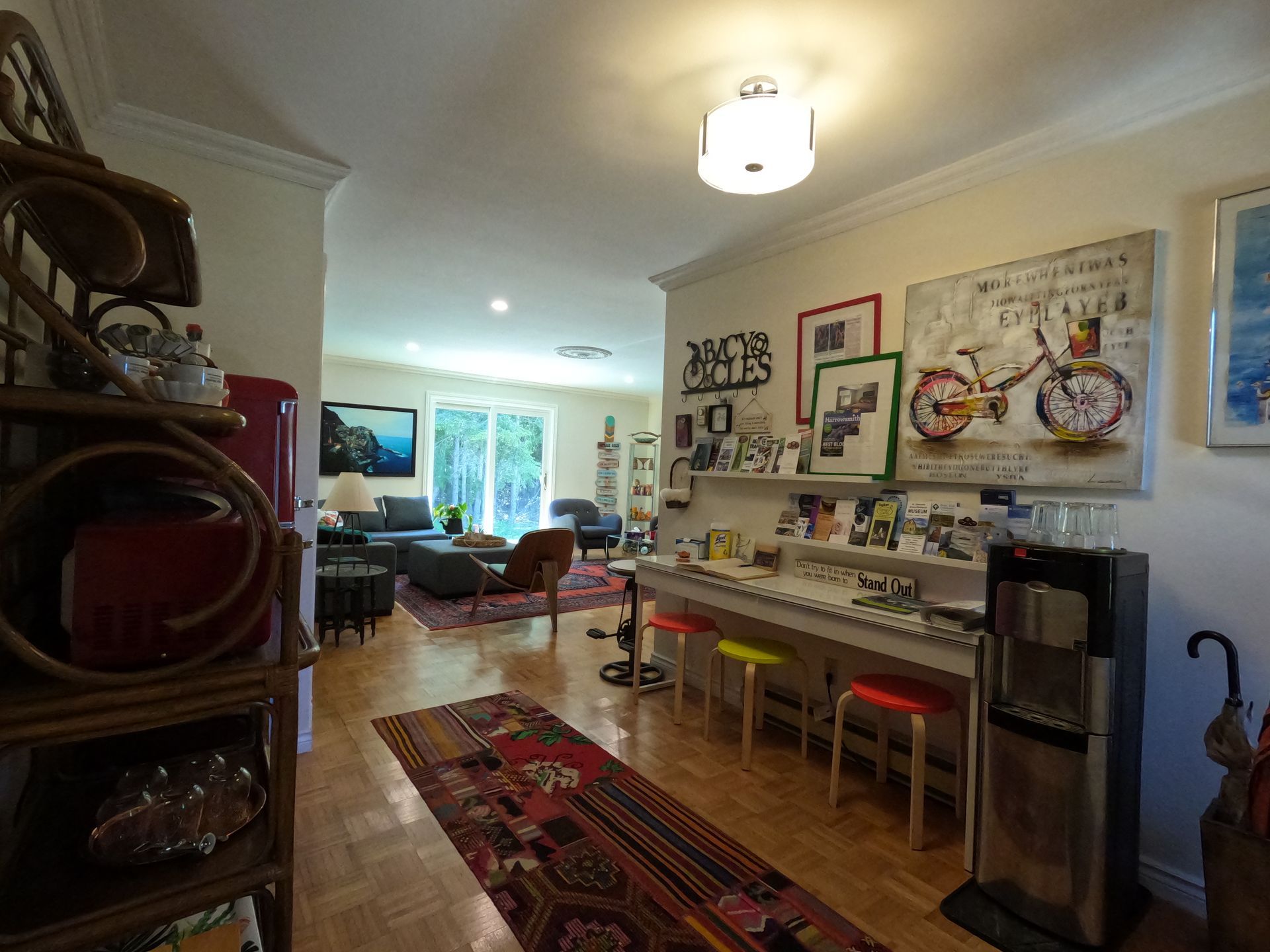 Bright living room with rugs, wall art, and a long desk beneath a window.