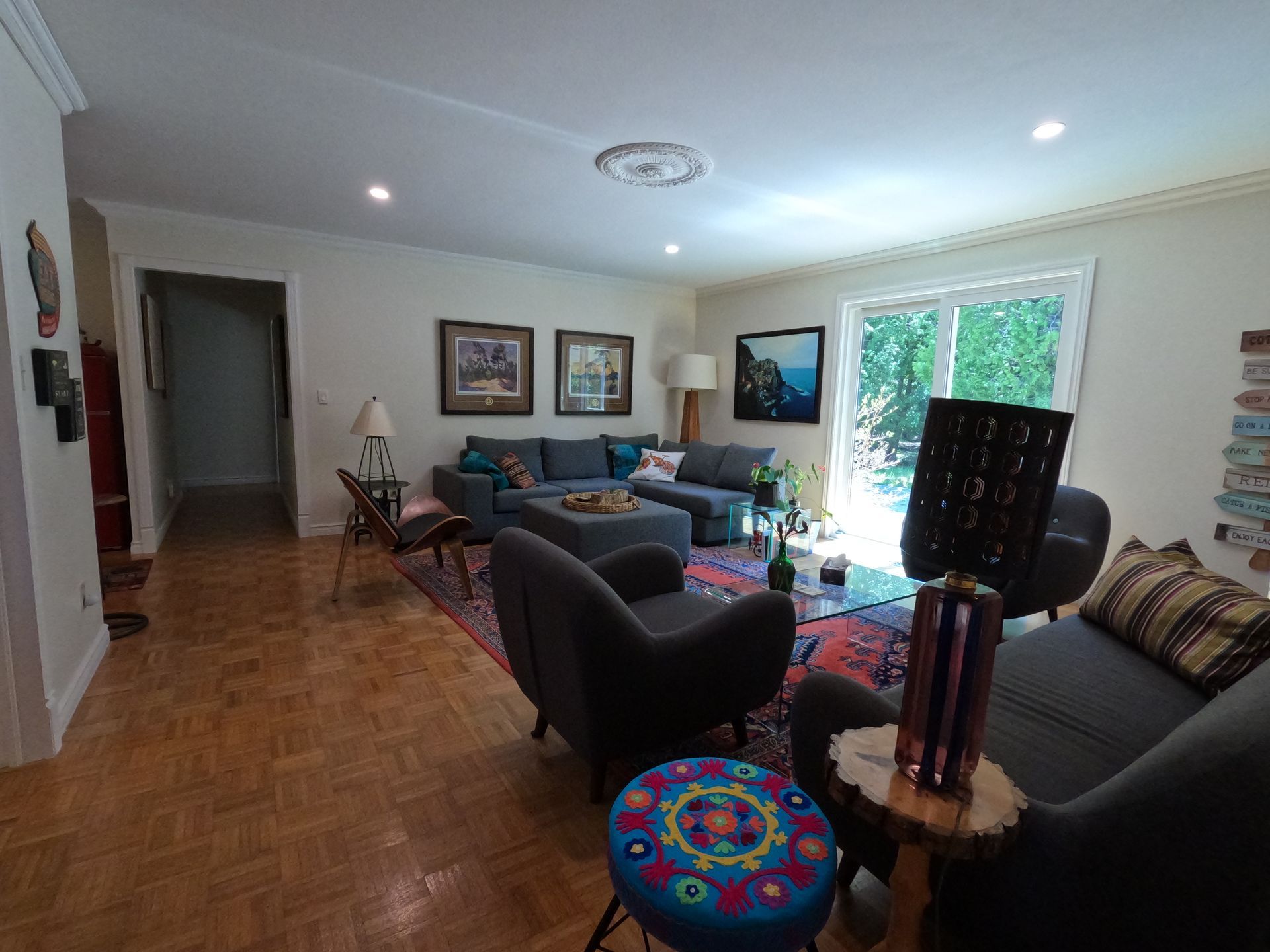 Bright living room with sofas, colorful rug, framed art, and sunlight through a window.