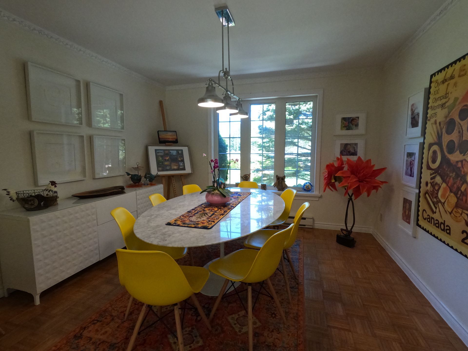Dining room with yellow chairs, a set table, and a large window letting in daylight.