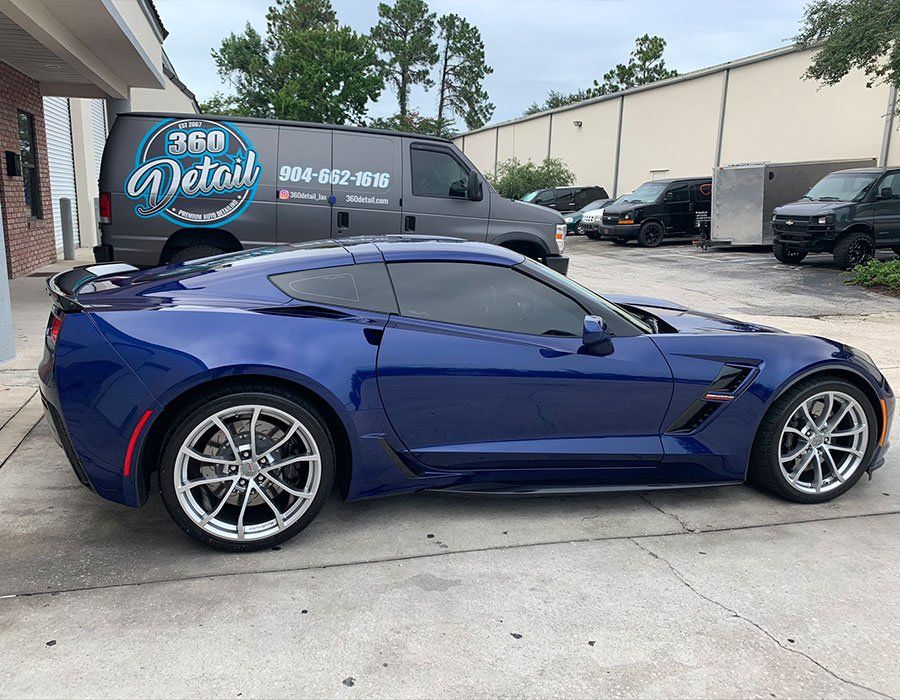 A blue sports car is parked in front of a van that says 360 detail.