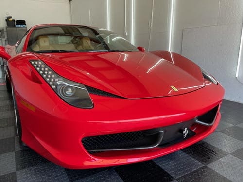 Red sports car parked indoors in a garage, front view.