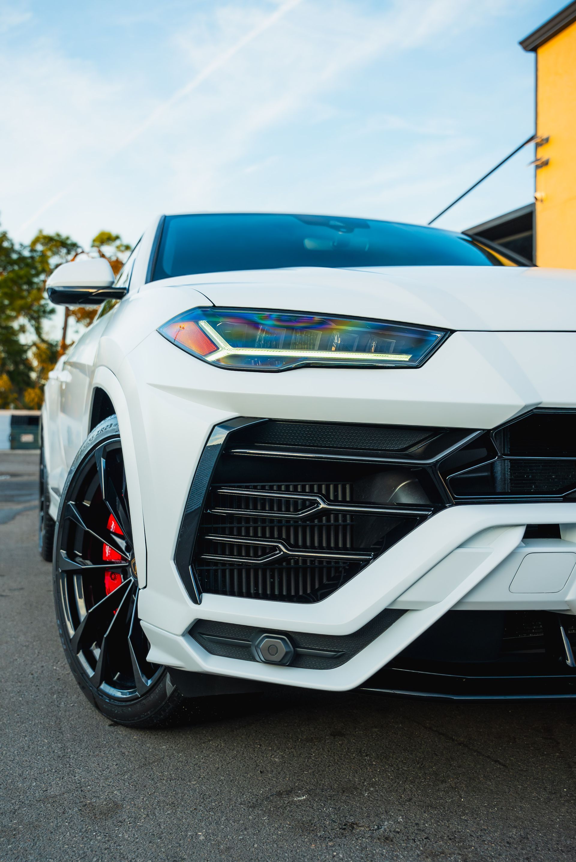 White sports car parked outdoors, front angle with black wheels and red brake calipers.