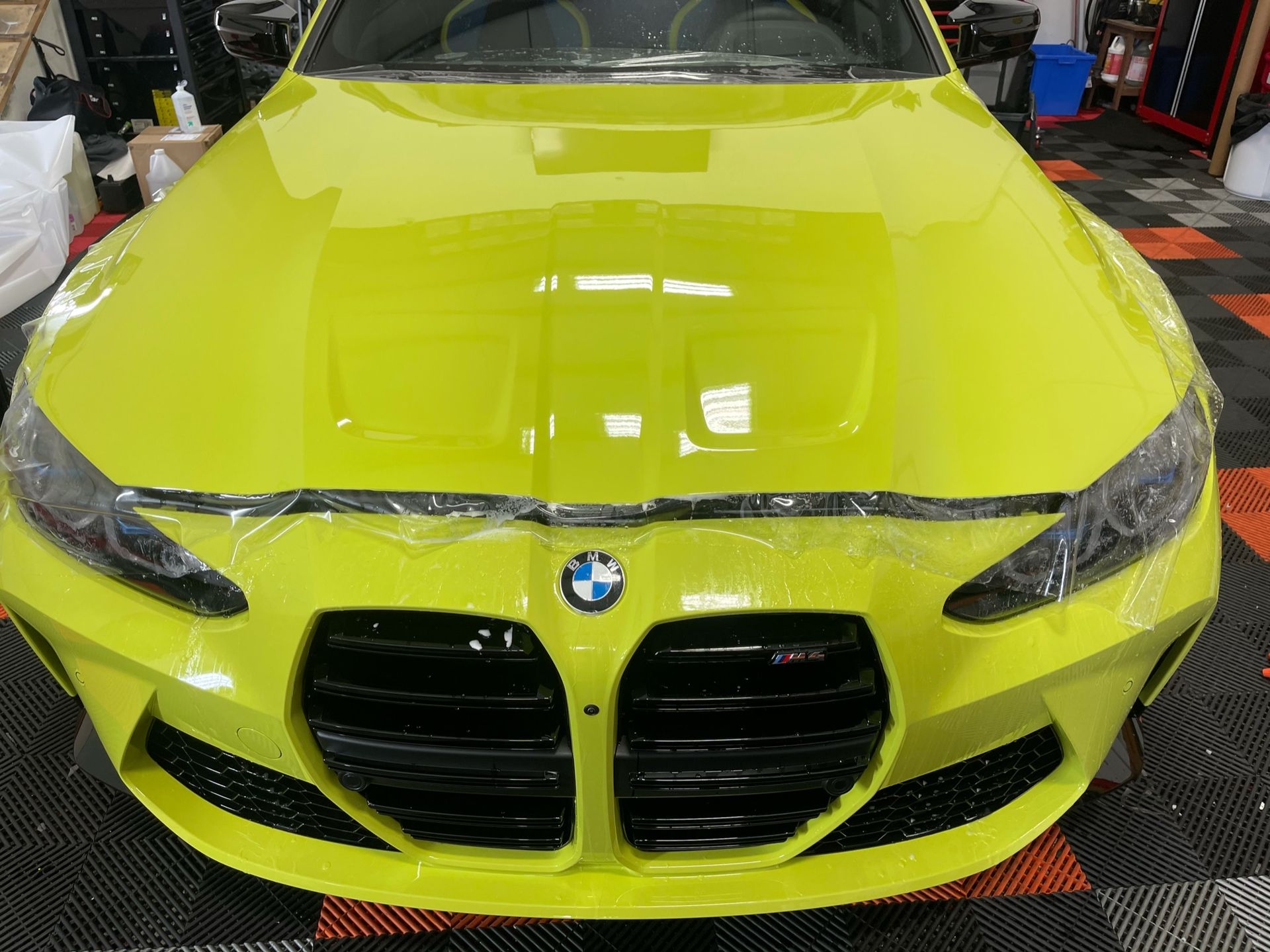 Luxury car receiving professional PPF maintenance with soft microfiber tools and low-pressure washing, extending paint protection film’s lifespan in Florida’s climate.