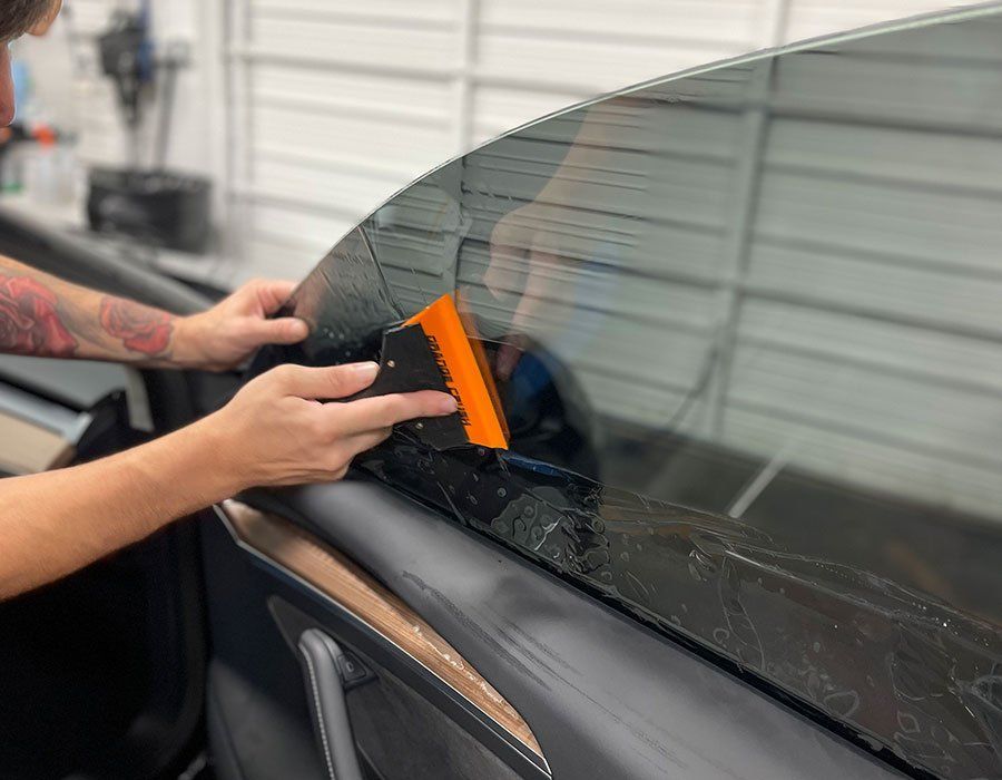 Close-up of tinted car windows in bright Florida sunlight showing protection against UV rays and interior fading.