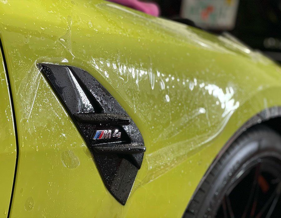 The fender of a yellow bmw m4 is covered in plastic.