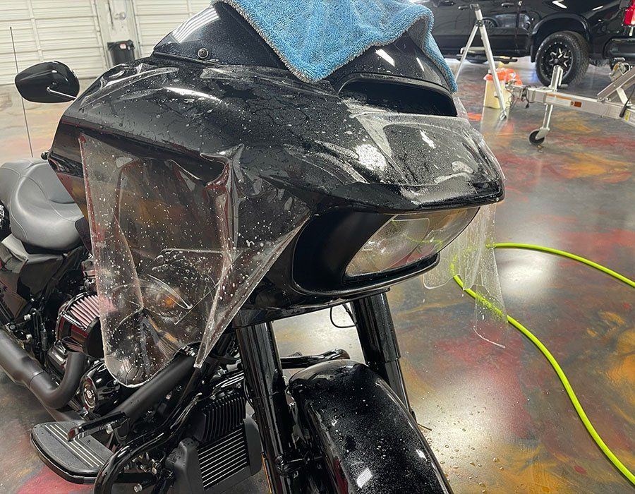 a black motorcycle with a blue towel on top of it is sitting in a garage .