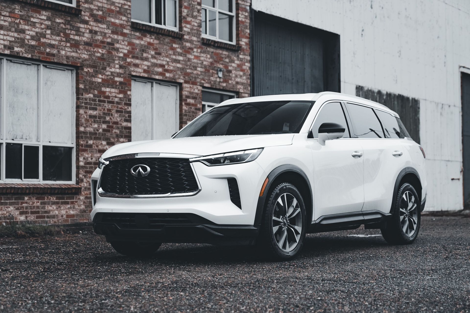 White Toyota SUV parked beside a brick building on a wet street