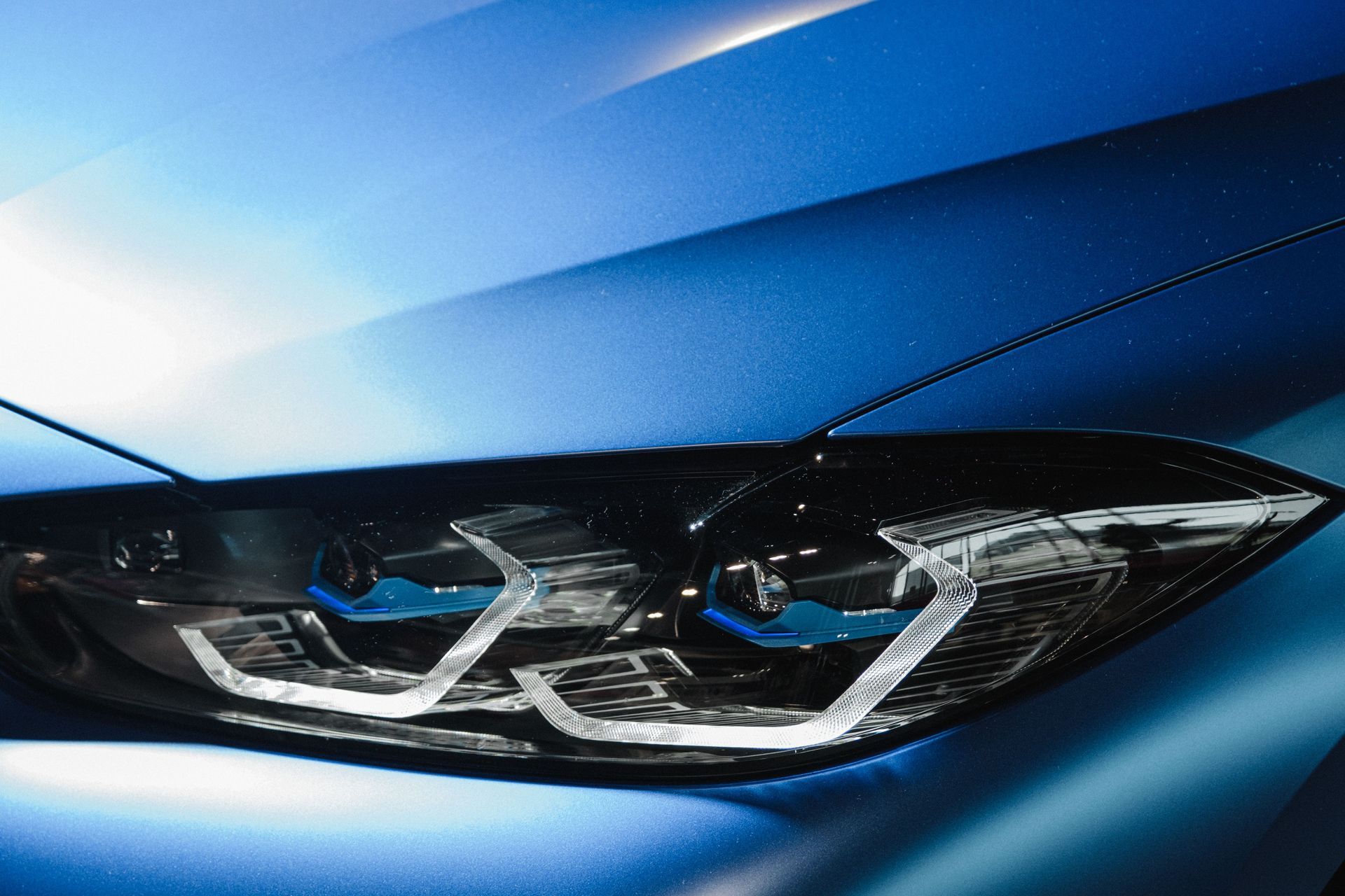 Close-up of a blue car’s sleek headlight with chrome details