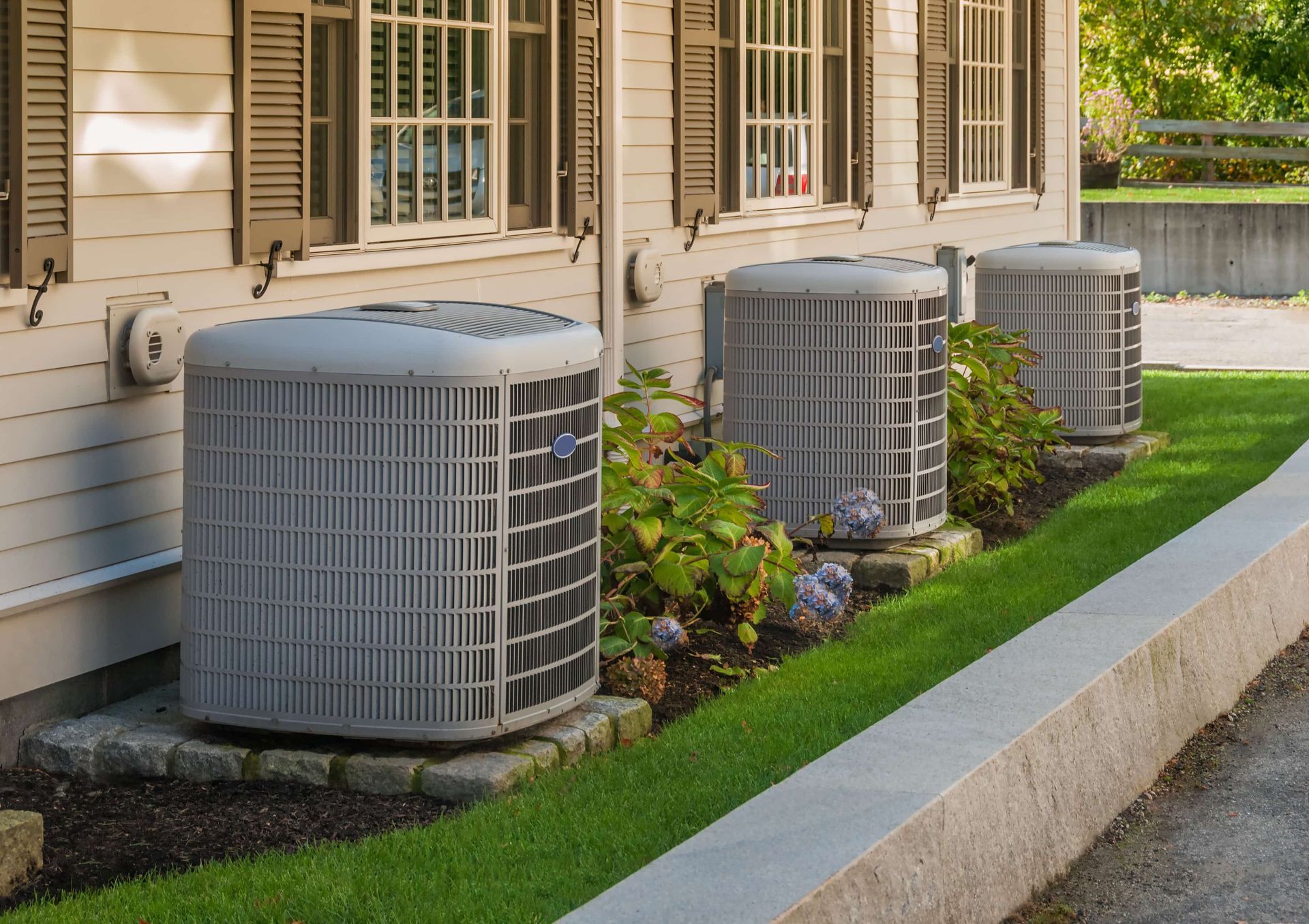 A row of air conditioners on the side of a house.