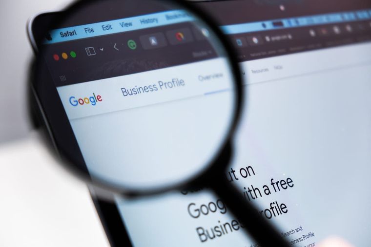 Magnifying glass over a laptop screen showing Google Business Profile webpage