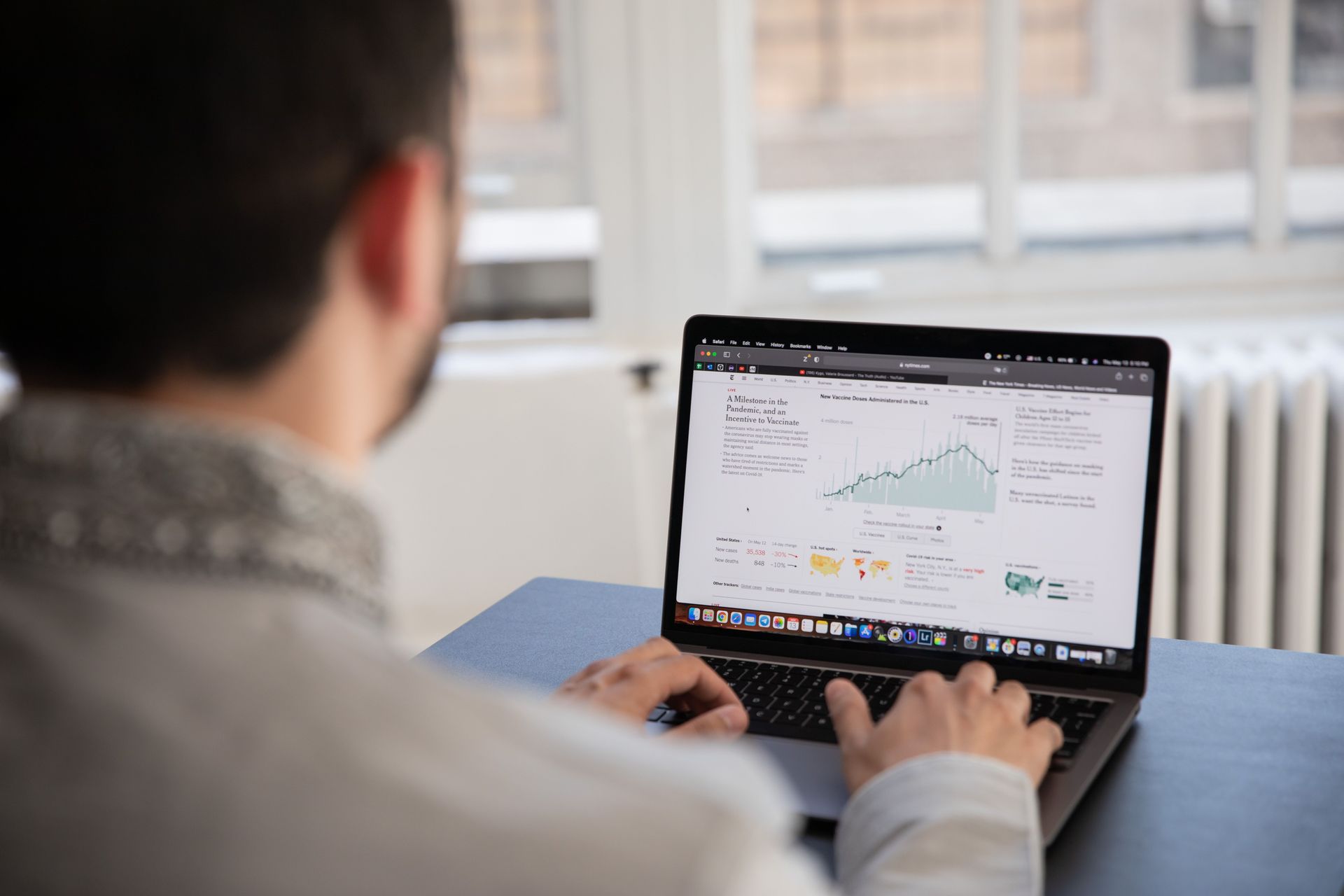 Person typing on a laptop with a large spreadsheet in a bright office setting.