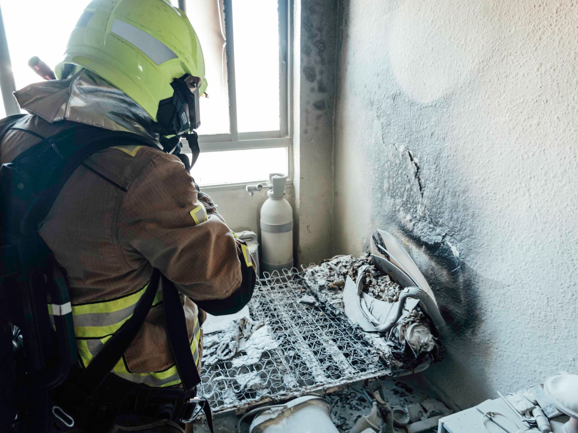 a fireman in a helmet is standing in a room next to a window .