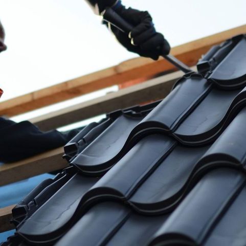 a man is working on a roof with a drill .
