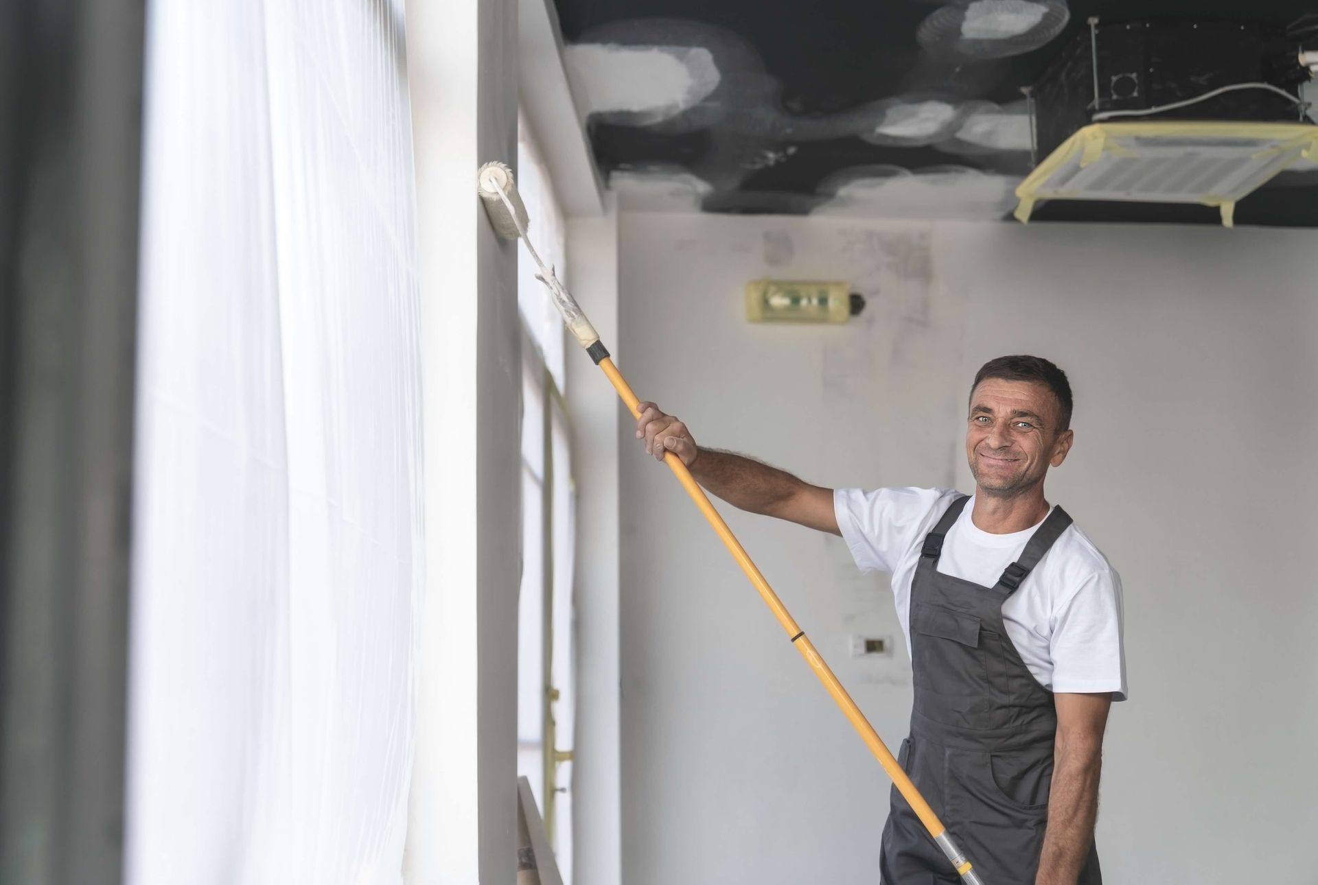 a man is painting a wall with a paint roller .